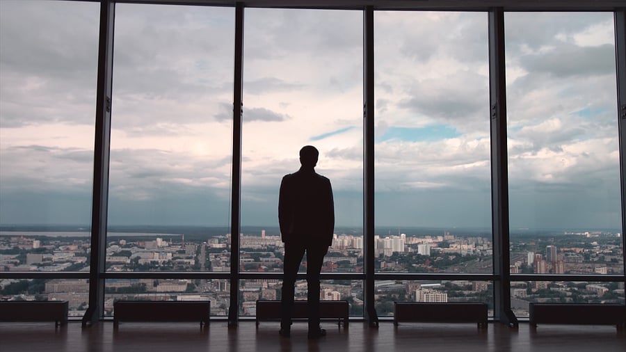 Silhouette of a person standing before a city skyline window