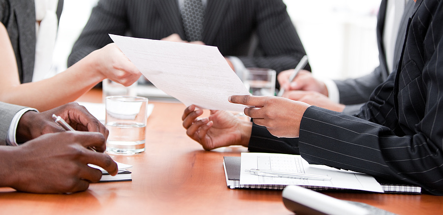 Colleagues passing a document across a conference table