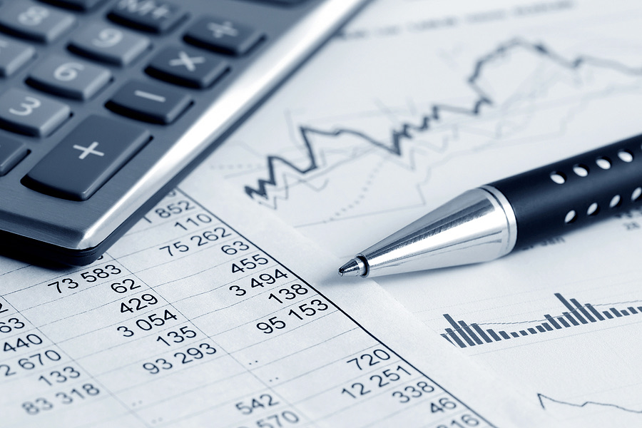 Calculator and pen resting on financial charts and reports