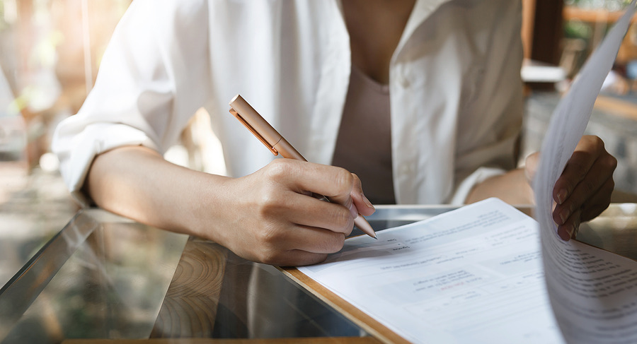 Close-up of a hand signing a document outdoors