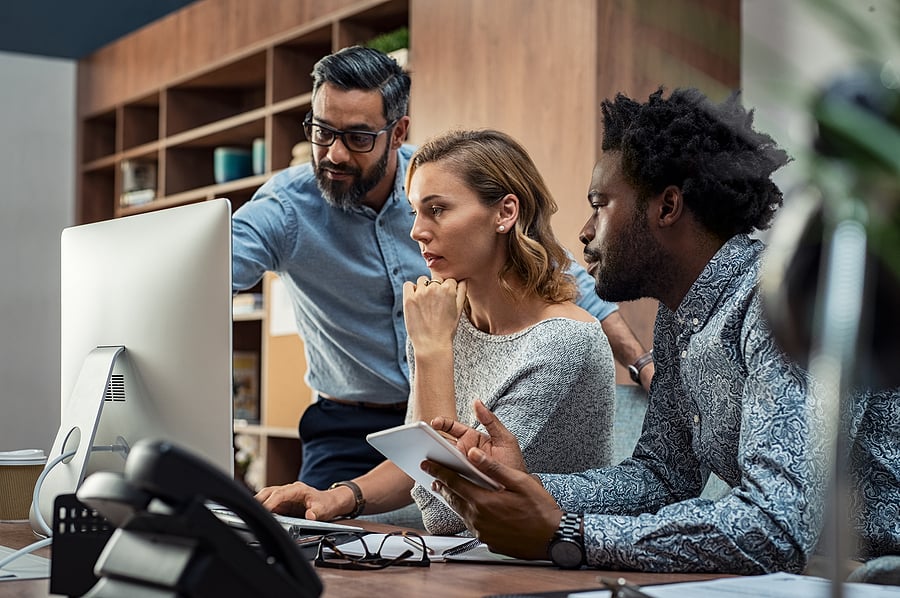 Three colleagues reviewing information together on a computer screen