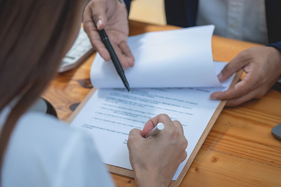 Two people reviewing and signing a legal document