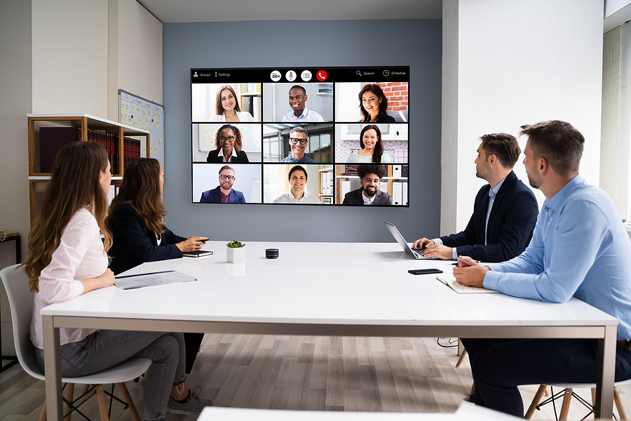 Colleagues in a conference room joining a video call on a screen