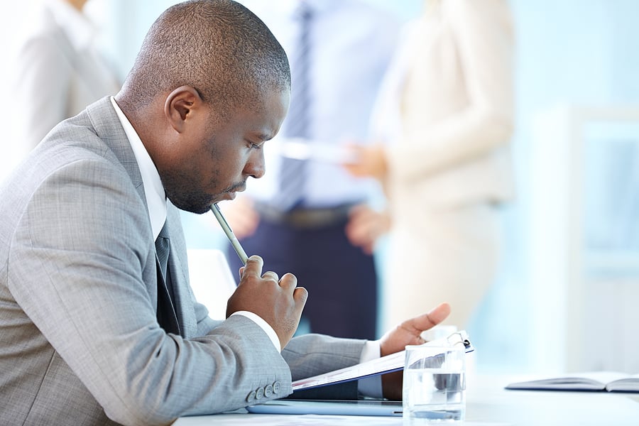 Businessman deep in thought while reviewing paperwork at a desk