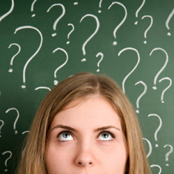 Woman looking up at question marks drawn on a chalkboard